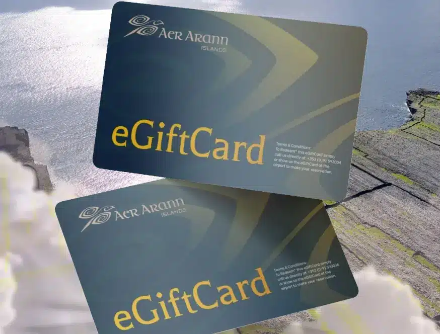 Two Aer Arann Islands eGift Cards are shown overlapping on a scenic background of cliffs, clouds, and the ocean. These dark Aran Islands Gift Cards feature gold text and a logo in the upper left corner.