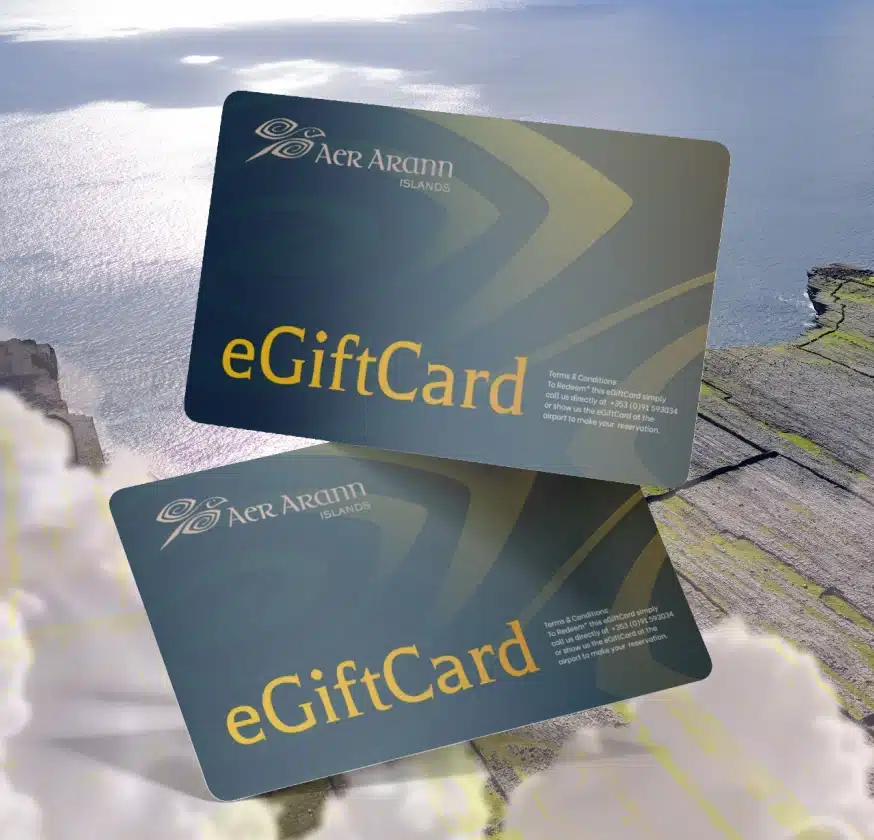 Two Aer Arann Islands eGift Cards are shown overlapping on a scenic background of cliffs, clouds, and the ocean. These dark Aran Islands Gift Cards feature gold text and a logo in the upper left corner.